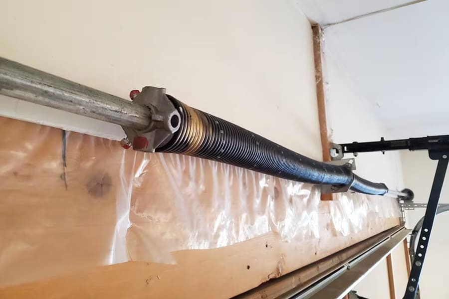 Technician replacing a broken torsion spring on a residential garage door